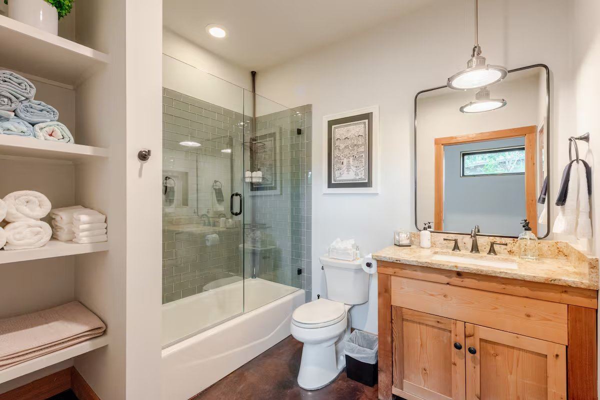 La Paz second bathroom — glass-enclosed tub and shower, granite vanity, and stacked linens in built-in shelving