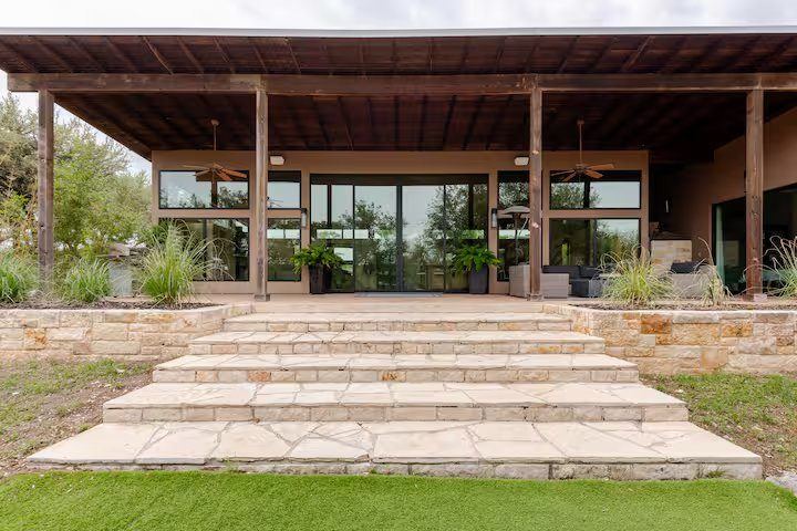 La Paz exterior — covered patio with wood ceiling, walls of glass, and limestone steps in the Wimberley Hill Country