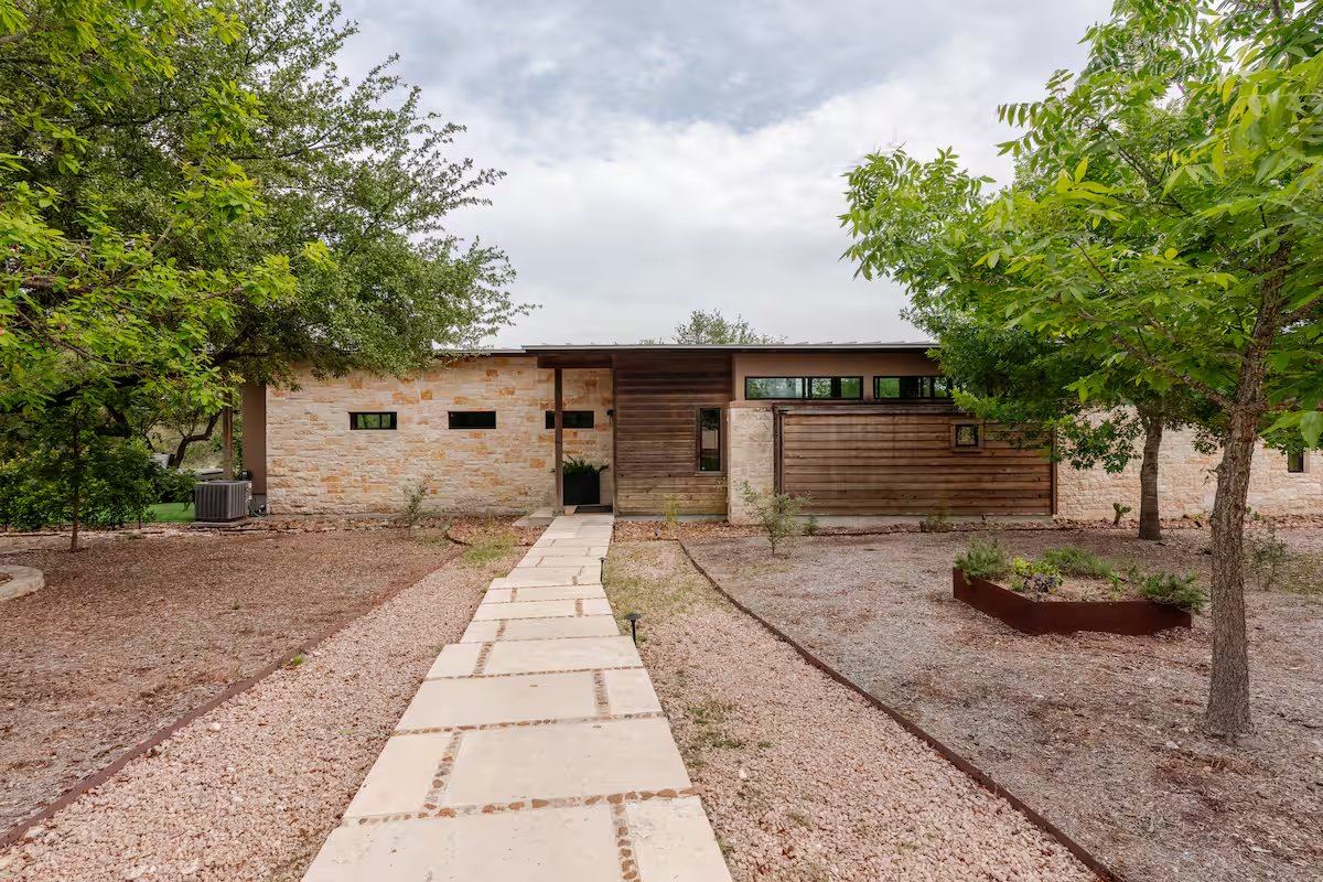 La Paz front exterior — stone and wood facade with limestone walkway flanked by oaks