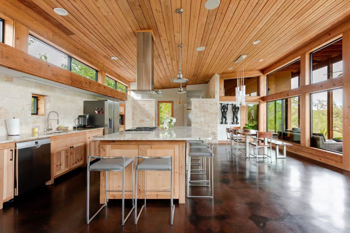 La Paz kitchen with island, breakfast bar stools, vaulted wood ceiling, and dining beyond
