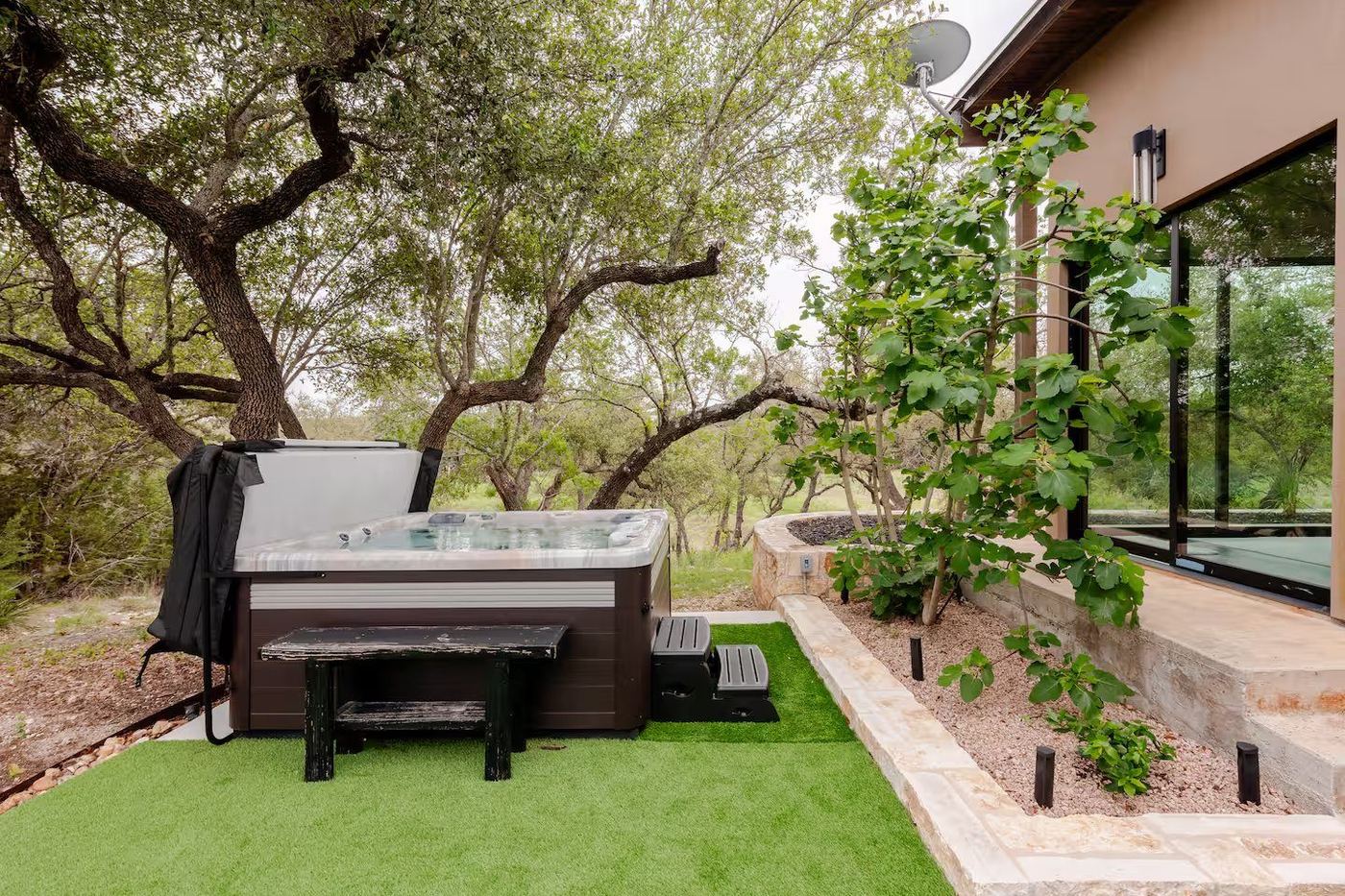 La Paz private hot tub on the deck, surrounded by live oaks under a Hill Country sky